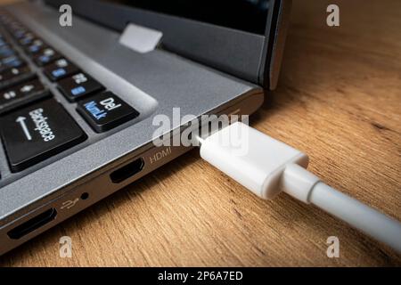 Cable USB adapter under the Type-C connector is installed in the laptop against the background of a wooden table Stock Photo