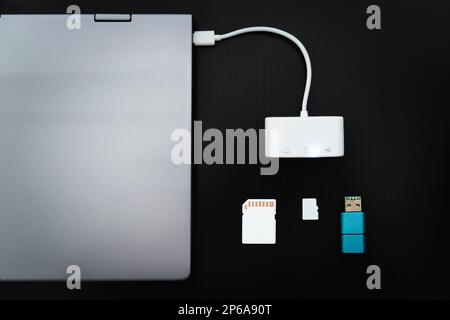 Laptop with USB Type-C adapter with pluged USB cables and SD card on a black background. Multiport station for laptop with multiple different ports. H Stock Photo