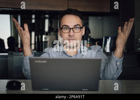 Outraged irritated young man with glasses, broker, businessman or manager, got financial loss, breakdown of the deal, displeased looks at the camera, Stock Photo