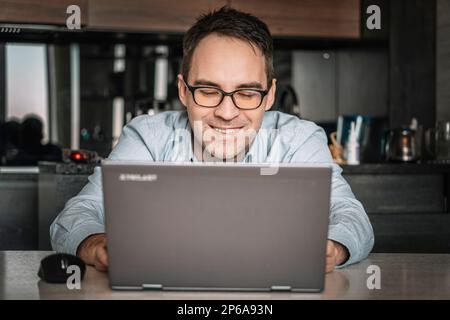 Happy confident businessman, entrepreneur, small business owner portrait at home office workplace. Young handsome freelance employee, student using la Stock Photo