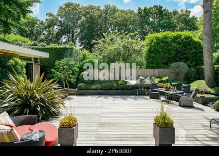 Amsterdam, Netherlands - 10 April, 2021: an outdoor living area with patio furniture and trees in the back yard, surrounded by lush green foliage on a sunny day Stock Photo