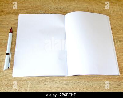 notebook with white pages and a pen on a wooden background Stock Photo