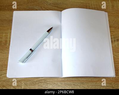 notebook with white pages and a pen on a wooden background Stock Photo