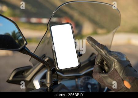 Close-up of a biker's hand pointing at the blank screen with mockup of his smartphone mounted on the scooter. Stock Photo
