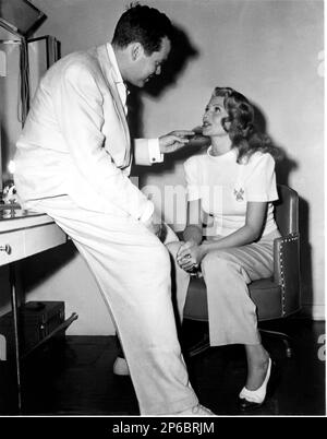 1947 , USA : The movie director and actor ORSON WELLES ( 1915 - 1985 ) with his wife RITA HAYWORTH ( 1918 - 1986 ) just before the filming together the movie  THE LADY FROM SHANGAI ( La Signora di Shangai )  by Orson Welles , and Rita became blonde. In this photo Rita Hatworth wear a pair of italian Salvatore FERRAGAMO shoes . - MOVIE - CINEMA - FILM - regista cinematografico - specchio - mirror - camerino - restroom - marito e moglie - sposi - coniugi - housband and wife - profilo - profile smile - sorriso - white dress - abito bianco vestito - smile - sorriso ---  Archivio GBB Stock Photo