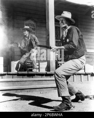 1959 , USA : The movie actor JOHN WAYNE with the rock n' roll singer  RICKY NELSON  ( 1940 - 1985 )  in RIO BRAVO   ( Un dollaro d' onore )  by Howard Hawks , United Artists pubblicity still . - CINEMA  - FILM - portrait - ritratto - sparatoria - arma - armi - fucile - rifle - gun - pistola - pistol - revolver - western - cowboy - POP MUSIC - MUSICA - sceriffo - hat - cappello - jeans - bandanna ----  Archivio GBB Stock Photo