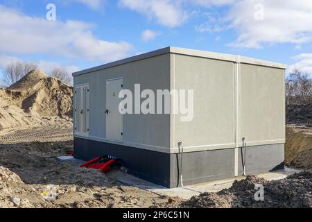 Unfinished modern large outdoor electric high voltage power distribution box in a new industrial facility, new transformer building Stock Photo