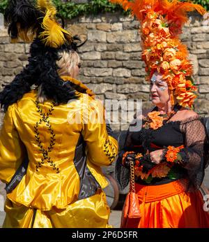 Two flamboyantly dressed women having a conversation in the street. Stock Photo