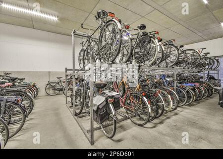 Amsterdam, Netherlands - 10 April, 2021: many bikes parked in a storage room with one bicycle on the top rack and another bike sitting on the bottom shelf Stock Photo