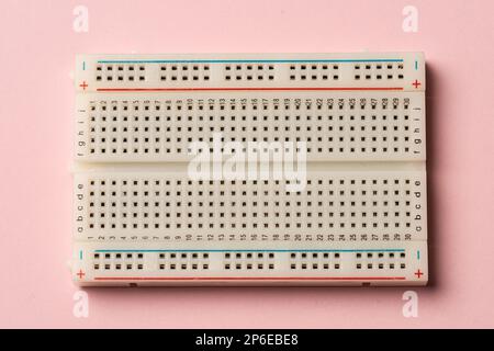 An electronics breadboard on pink background. Stock Photo