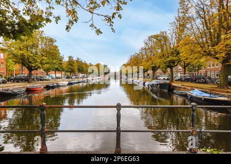 Amsterdam, Netherlands - 10 April, 2021: a canal with boats in the water and autumn leaves on the trees lining the waterway, amsterdam, netherlands stock photo Stock Photo