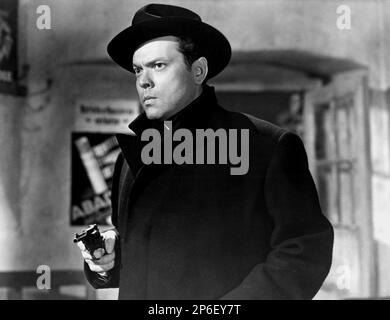 1949 : The  movie actor ORSON WELLES ( 1915 - 1985 )  in a pubblicitary shot  for THE THIRD MAN ( Il terzo uomo ) by Carol Reed , from a novel by Graham Greene - FILM NOIR  - CINEMA - ATTORE CINEMATOGRAFICO - collar - colletto - hat - cappello - weapon - arma - pistola - pistol - revolver - cappotto - coat - FILM - TRILLER - SUSPANCE   ----  Archivio GBB      Archivio Stock Photo