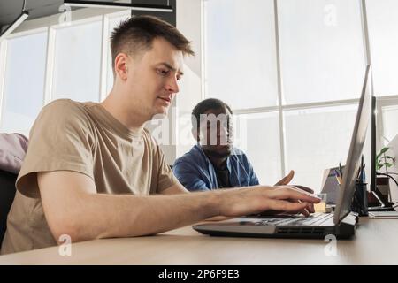 Two programmers working in the office of a software development company. Coding technologies, site design. Successful diverse Teamwork. Cyberspace Stock Photo