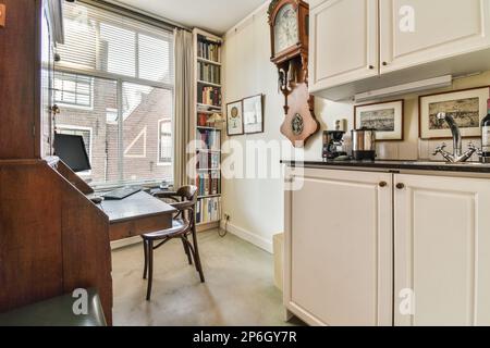 Amsterdam, Netherlands - 10 April, 2021: a kitchen with white cabinets and an old clock hanging on the wall in the corner of the room is visible Stock Photo