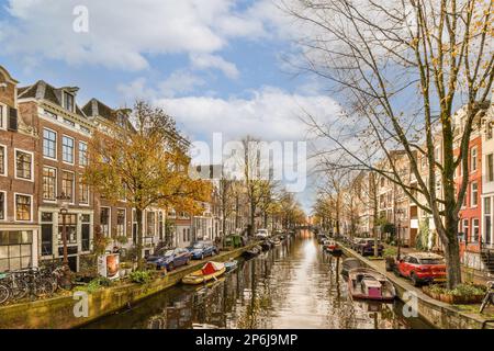 a canal with boats on the water and buildings in the background, taken from a boat tour through amsterdam's canals Stock Photo