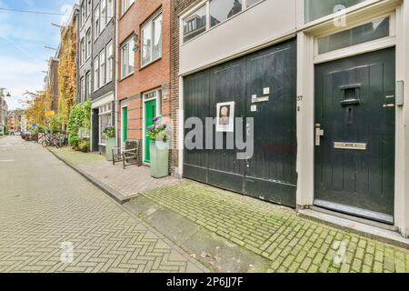 Amsterdam, Netherlands - 10 April, 2021: an empty street in the middle of a small town with bricked buildings on both sides and green doord windows Stock Photo