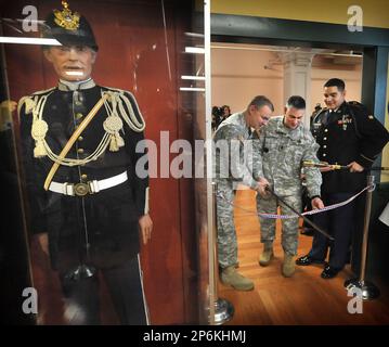 Col. Thomas Brittain, left, cuts the ribbon with a sword with help from  Command Sgt. Major Matthew Barnes, center, and Specialist Stafford Smith  during the Ribbon Cutting Ceremony at the remodel Lewis