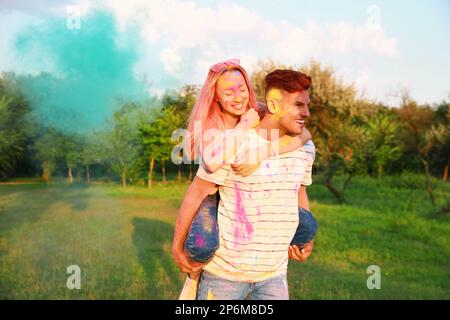 Happy couple covered with colorful powder dyes outdoors. Holi festival celebration Stock Photo