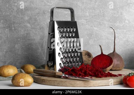 Grater and fresh ripe vegetables on table Stock Photo