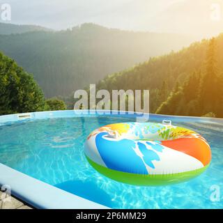 Colorful inflatable ring floating in outdoor swimming pool at luxury resort and beautiful view of mountains on sunny day Stock Photo