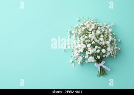 Beautiful gypsophila flowers tied with ribbon on turquoise background, top view. Space for text Stock Photo
