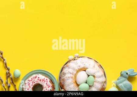 Composition with tasty Easter cakes and eggs on yellow background Stock Photo