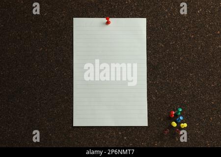 Blank paper sheet and pins on cork board Stock Photo