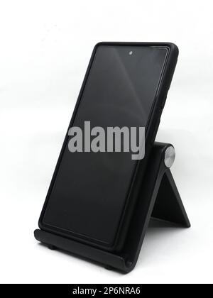 a smartphone placed on an adjustable mobile holder stand at an angle isolated in a white background Stock Photo