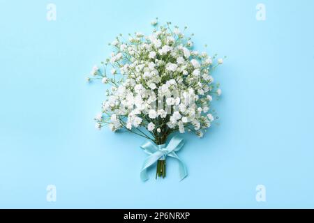Beautiful gypsophila flowers tied with ribbon on light blue background, top view Stock Photo