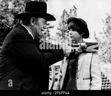 1969: The  celebrated movie actors  JOHN WAYNE with KIM DARBY in a pubblicitary shot for the movie TRUE GRIT ( IL GRINTA ) by Henry Hathaway  , from a novel byCharles Portis  - CINEMA - ATTORE CINEMATOGRAFICO - COWBOY - WESTERN - hat - cappello -  FILM - pistola - revolver - gun - pistol  ---- Archivio GBB Stock Photo