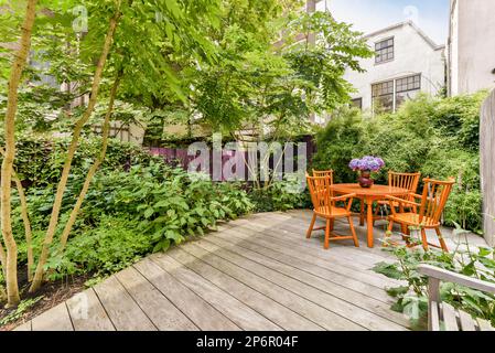 Amsterdam, Netherlands - 10 April, 2021: an outside area with some chairs and plants on the side of the house, including a table and two orange chairs Stock Photo