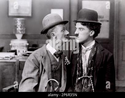 1915 : The silent movie actor and movie director CHARLES CHAPLIN ( 1889 - 1977 ) with BEN TURPIN in HIS NEW JOB - CINEMA - FILM - portrait - ritratto - hat - cappello - regista cinematografico - attore - attrice - comico - tie - papillon - cravatta - collar - colletto - sigaretta - cigarette - fumo - smoke - baffi - moustache ---- Archivio GBB      Archivio Stock Photo
