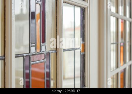 Amsterdam, Netherlands - 10 April, 2021: several different colored glass windows in a room with white walls and red trim around the window panes on the wall Stock Photo