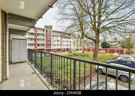 Amsterdam, Netherlands - 10 April, 2021: an outside area with cars parked in the parking lot and trees on the other side of the building, as seen from the balcony Stock Photo