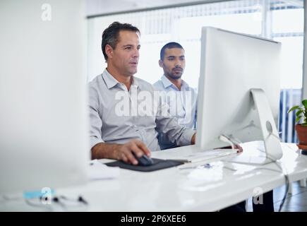 Two minds are better than one. two creative businesspeople working together on a computer in the office. Stock Photo