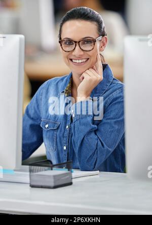 Feeling great about her prospects. Smiling businesswoman working at her desk, looking at the camera. Stock Photo