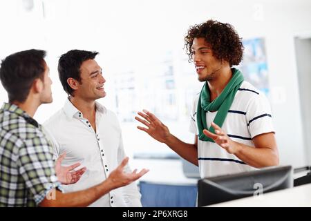 Just listen to my idea...Three male colleagues working in the office together. Stock Photo