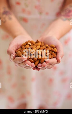 Want some almonds. a bunch of almonds in a persons cupped hands. Stock Photo