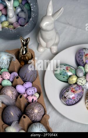 photo painted in different colors eggs and ceramic rabbit on the table Stock Photo
