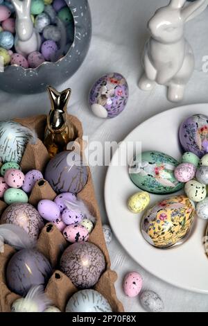 photo painted in different colors eggs and ceramic rabbit on the table Stock Photo