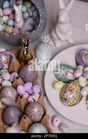 photo colorful decorative chicken and quail eggs and a ceramic rabbit on the table Stock Photo