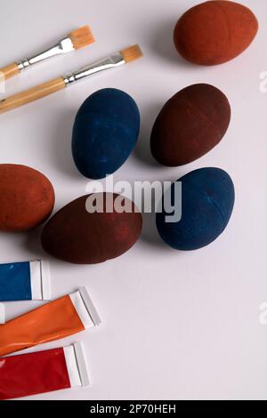 photo of several painted eggs with paints in a tube and brushes on a white background Stock Photo