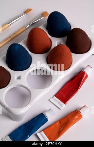 photo of several painted eggs with paints in a tube and brushes on a white background Stock Photo