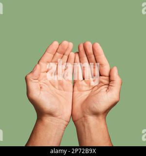 Hands, welfare and poverty with a man in studio on a green background begging for help or support. Hope, community and palm cupping with a person Stock Photo