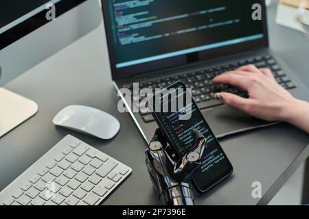 Close-up of developer typing security codes on smartphone and laptop for new computer program Stock Photo