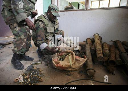 In a handout photograph released by the African Union-United Nations Information Support Team Monday, Aug.15, 2011, Ugandan soldiers serving with the African Union Mission in Somalia (AMISOM) sort through a bag of hand grenades and other munitions that were used by the extremist group Al Shabaab to make improvised explosive devices. AMISOM troops and Transitonal Federal Government (TFG) forces dislodged remnants of Al Shabaab from the site following the withdrawal of most of the extremist group's forces from the city ten days ago, discovering the bomb making facility at the former steel factor