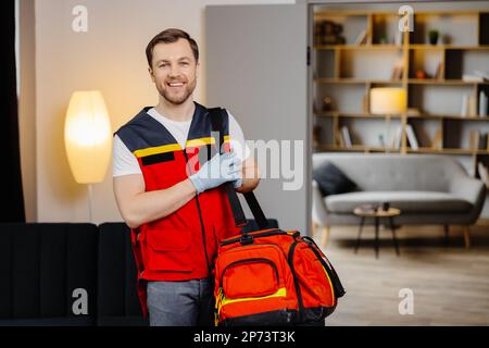 First aid course. A young male paramedic with a bag on his shoulders is standing in a classroom before a lecture. Stock Photo