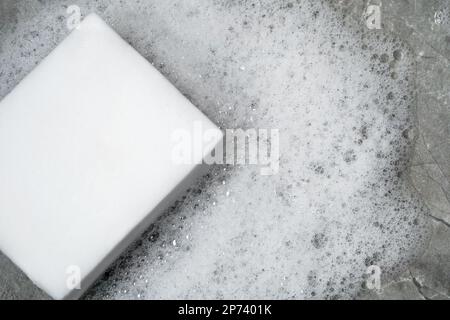 Close up photo white sponge and foam or soap bubbles as a symbol of hygiene and sanitation. Concopt of cleanup and washing service. Stock Photo