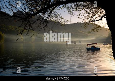 Paddleboats on the lake with haze at sunset. Leisure time activity or holidays concept photo. Stock Photo