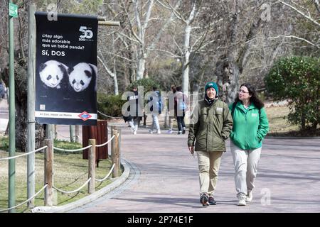(230308) -- MADRID, March 8, 2023 (Xinhua) -- Visitors walk past a poster showing images of giant panda twins at Zoo Aquarium in Madrid, Spain, March 7, 2023. Thanks to close cooperation between Zoo Aquarium and China Conservation and Research Center for the Giant Panda, specialists and staff members managed to breed this extremely rare species in a country far away from its homeland. You You and Jiu Jiu were born to Hua Zuiba and her partner Bing Xing in September, 2021. This giant panda family is cordially deemed a bridge of friendship between Spain and China. (Photo by Gustavo Valiente/Xinh Stock Photo